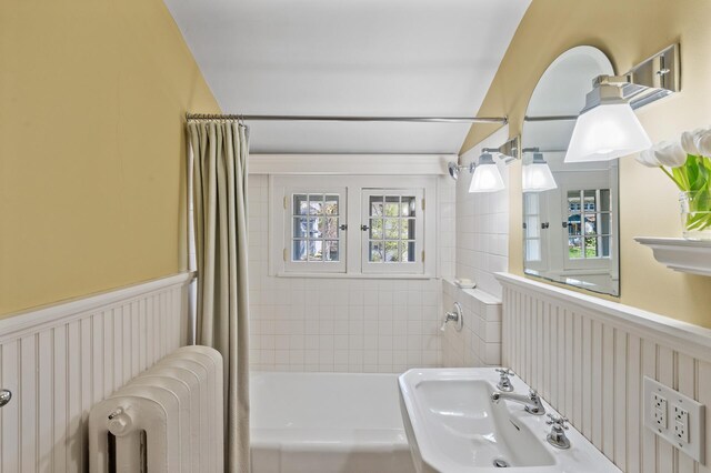 full bath with radiator, shower / bathtub combination with curtain, and wainscoting