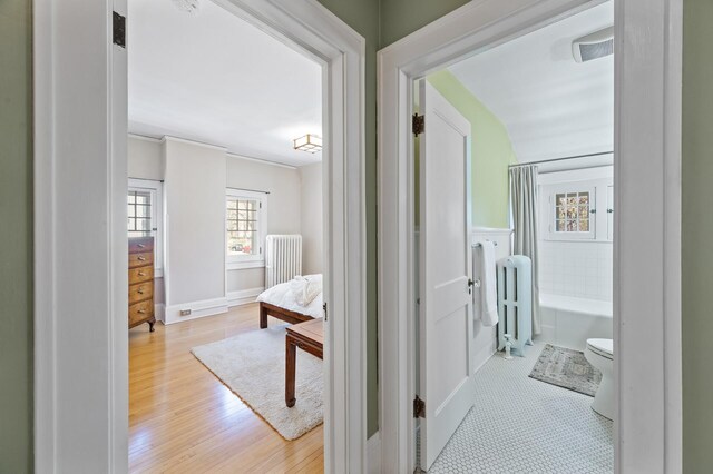 hall featuring baseboards, wood finished floors, and radiator