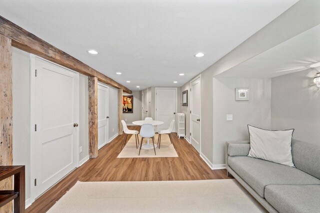living area featuring baseboards, recessed lighting, light wood-style flooring, and radiator