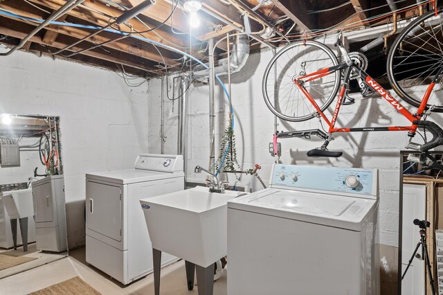 clothes washing area with laundry area, a sink, and washing machine and dryer