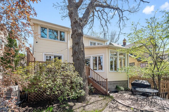 rear view of house featuring a patio, a sunroom, fence, and stairway