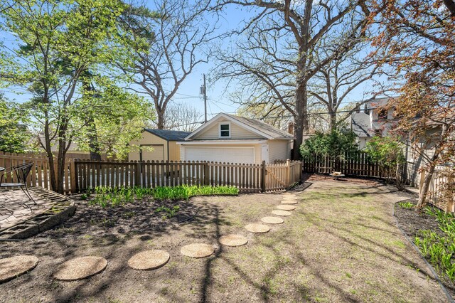 view of yard featuring a detached garage, an outbuilding, and a fenced front yard