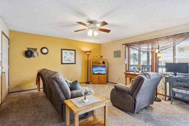 living room with a textured ceiling, carpet flooring, and ceiling fan