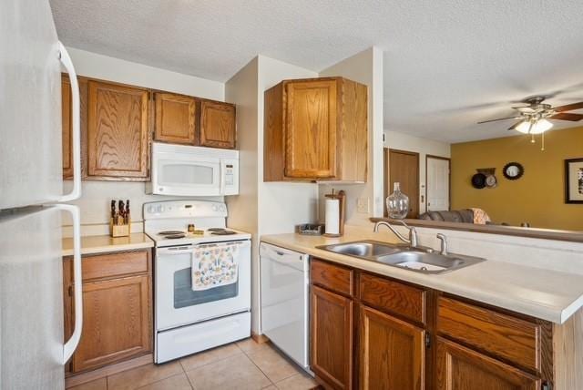 kitchen with light countertops, brown cabinetry, a sink, and white appliances