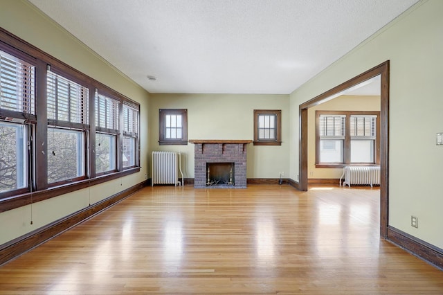 unfurnished living room with radiator heating unit, light wood finished floors, and baseboards