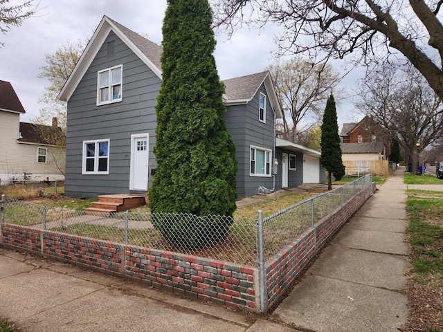 view of front of home with a fenced front yard and a shingled roof