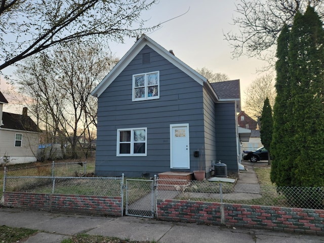 traditional home featuring a fenced front yard, a gate, and central AC