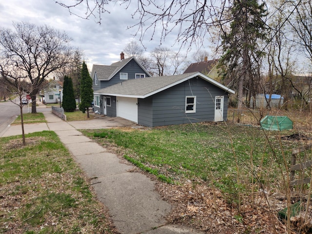 view of side of home with concrete driveway, roof with shingles, and a chimney