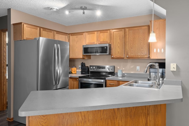 kitchen with a peninsula, appliances with stainless steel finishes, a sink, and light countertops