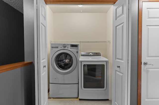 laundry room featuring separate washer and dryer, a textured ceiling, and laundry area