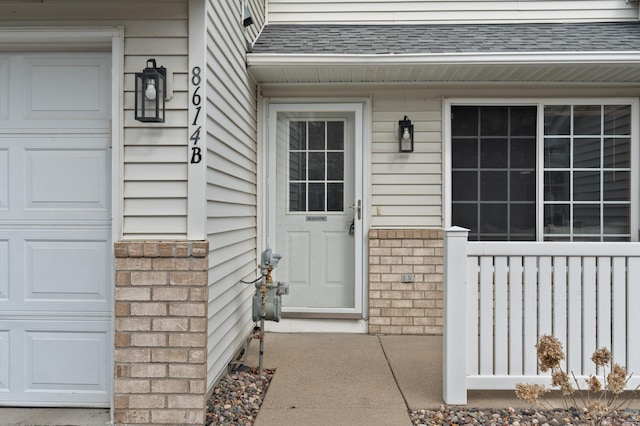 entrance to property with brick siding and a garage