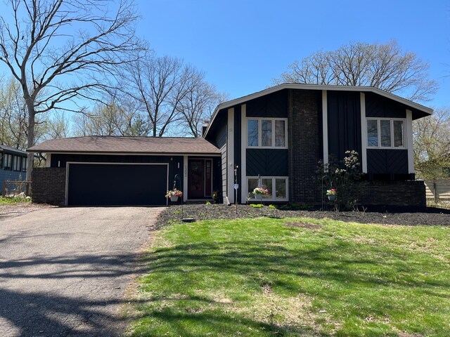 split level home with board and batten siding, brick siding, an attached garage, and aphalt driveway