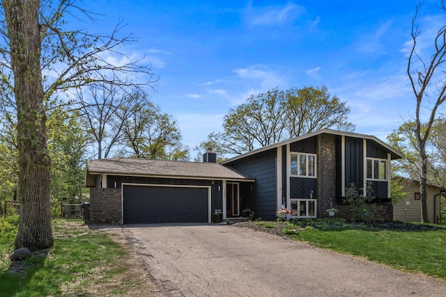 1302 Birch Dr, Hudson, WI 54016 - view of front facade featuring an attached garage, brick siding, a chimney, driveway, and a front yard