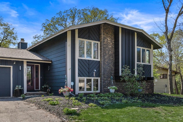 1302 Birch Dr, Hudson, WI 54016 - view of front of house with board and batten siding, a chimney, brick siding, and an attached garage