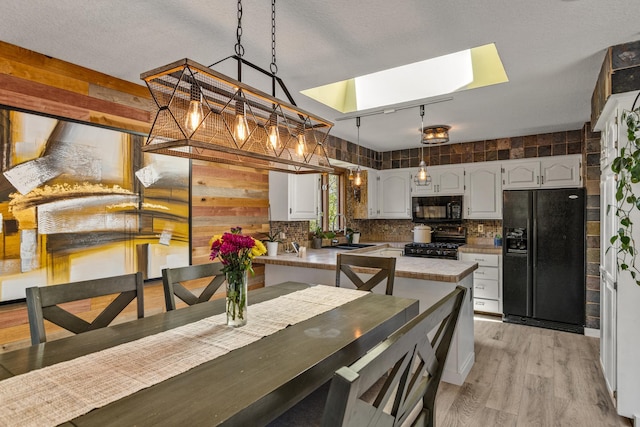 1302 Birch Dr, Hudson, WI 54016 - kitchen featuring black appliances, a sink, a skylight, white cabinets, and tasteful backsplash
