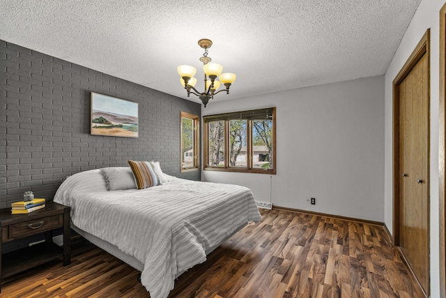 1302 Birch Dr, Hudson, WI 54016 - bedroom with a chandelier, wood finished floors, brick wall, a textured ceiling, and baseboards