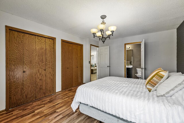 1302 Birch Dr, Hudson, WI 54016 - bedroom featuring wood finished floors, two closets, a chandelier, ensuite bath, and a textured ceiling