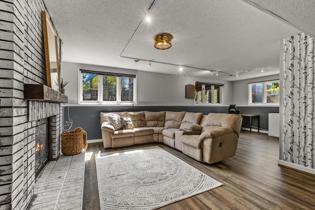 1302 Birch Dr, Hudson, WI 54016 - living area featuring rail lighting, wood finished floors, a textured ceiling, baseboards, and a brick fireplace