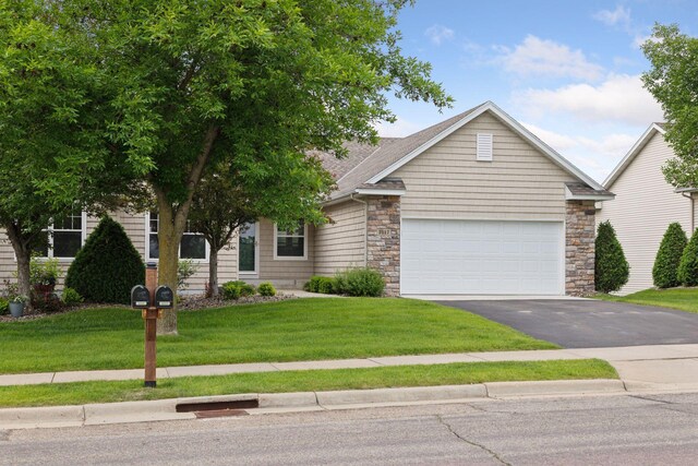 2117 14th St NE, Faribault, MN 55021 - view of front facade featuring asphalt driveway, an attached garage, a front yard, and stone siding