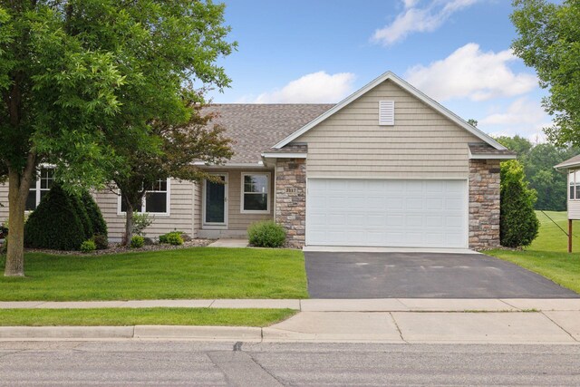 2117 14th St NE, Faribault, MN 55021 - view of front facade featuring driveway, a front lawn, an attached garage, and roof with shingles