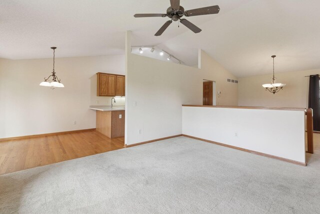 2117 14th St NE, Faribault, MN 55021 - unfurnished living room with lofted ceiling, light colored carpet, ceiling fan, and a chandelier