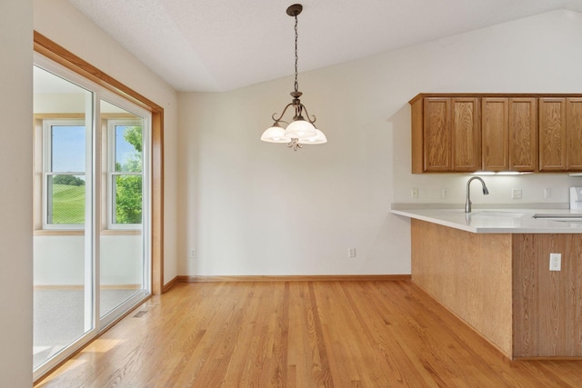 2117 14th St NE, Faribault, MN 55021 - kitchen with brown cabinets, light wood-style floors, light countertops, a chandelier, and vaulted ceiling