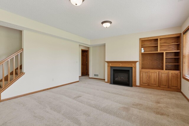 2117 14th St NE, Faribault, MN 55021 - unfurnished living room with carpet flooring, stairway, a fireplace with flush hearth, and a textured ceiling