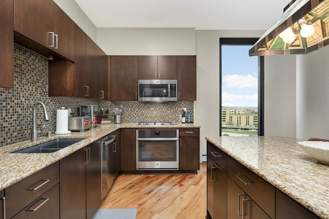 1240 2nd St Unit 701, Minneapolis, MN 55415 - kitchen with stainless steel appliances, a sink, light wood-style flooring, and decorative backsplash
