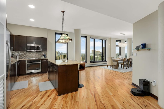 1240 2nd St Unit 701, Minneapolis, MN 55415 - kitchen featuring appliances with stainless steel finishes, light wood-style floors, dark brown cabinetry, decorative backsplash, and a kitchen island