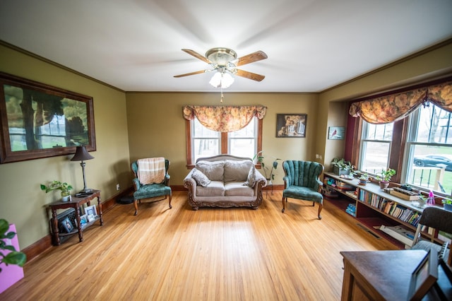 living room with ornamental molding, a ceiling fan, and wood finished floors