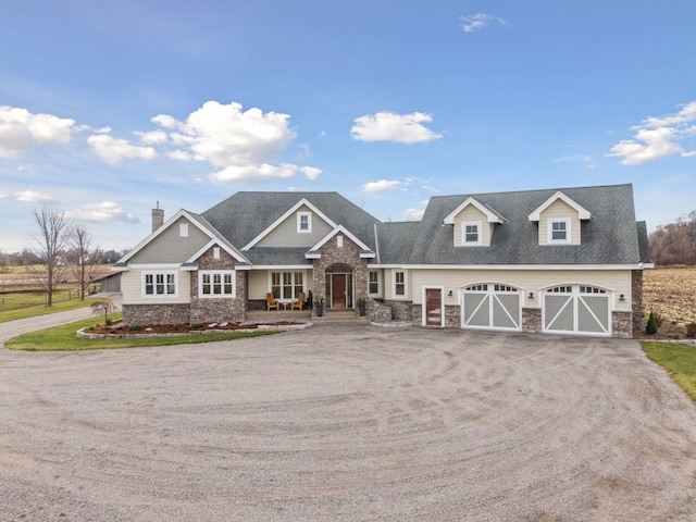 craftsman inspired home with a chimney, a garage, driveway, and stone siding