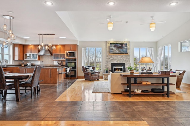 living area featuring recessed lighting, a stone fireplace, and a healthy amount of sunlight