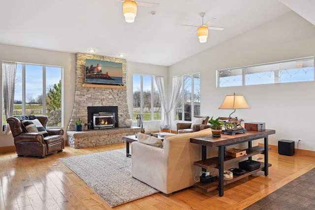 living room with a stone fireplace, ceiling fan, vaulted ceiling, and hardwood / wood-style flooring