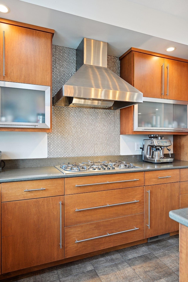 kitchen with gas cooktop, decorative backsplash, wall chimney exhaust hood, and brown cabinets