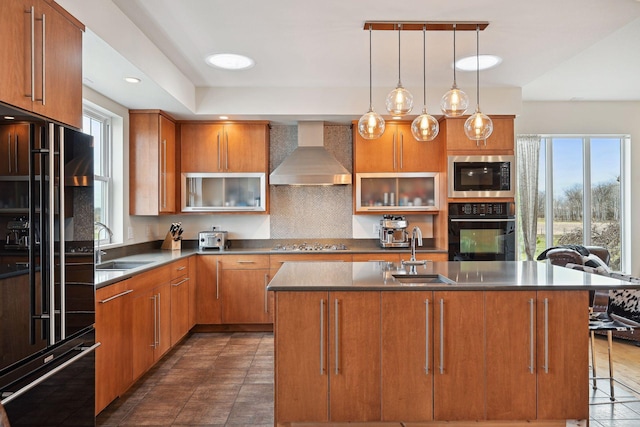 kitchen featuring a sink, decorative backsplash, black appliances, and wall chimney exhaust hood