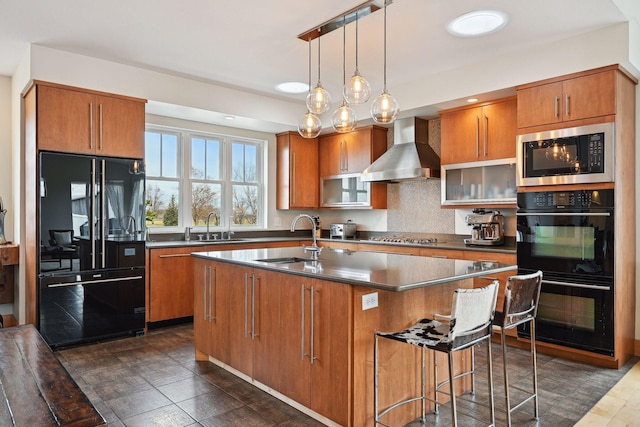 kitchen featuring dark countertops, wall chimney exhaust hood, brown cabinets, a sink, and black appliances