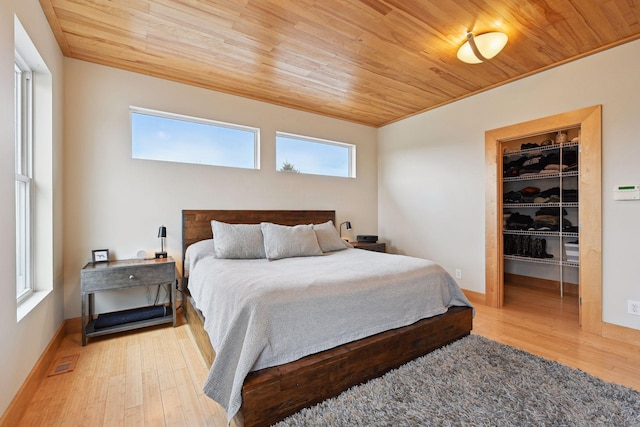 bedroom featuring visible vents, a walk in closet, wood finished floors, and wooden ceiling