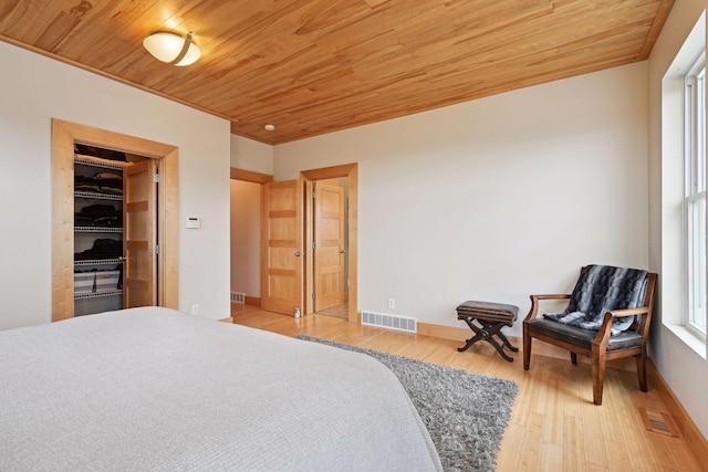 bedroom featuring wooden ceiling, a walk in closet, wood finished floors, and visible vents