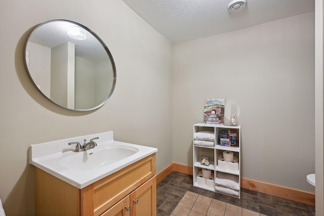 bathroom featuring a textured ceiling, baseboards, and vanity