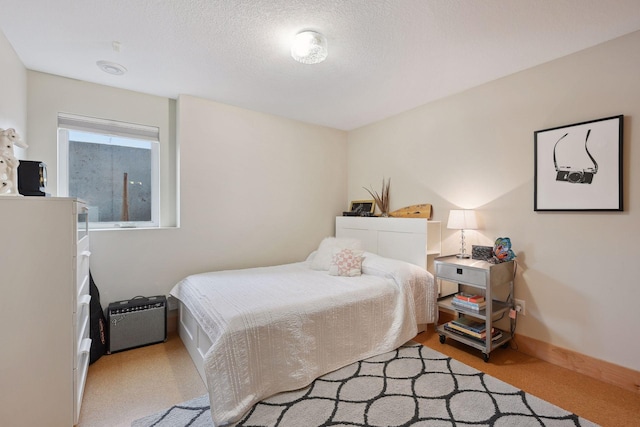 bedroom with a textured ceiling, light carpet, and baseboards