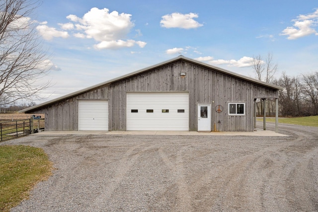 detached garage featuring fence and driveway