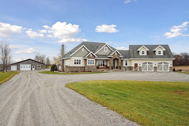 view of front facade featuring an outdoor structure, a front yard, stone siding, dirt driveway, and a detached garage