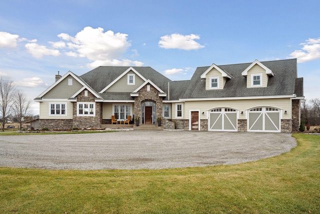 craftsman-style home featuring a front yard, driveway, stone siding, and a garage