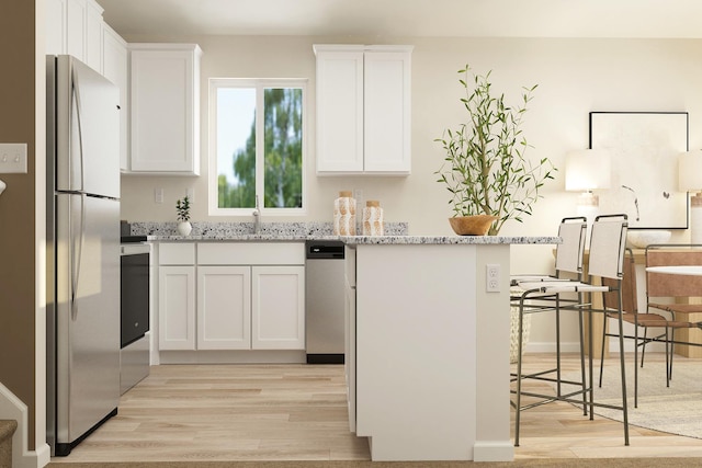 kitchen with light stone counters, light wood-style floors, a breakfast bar, white cabinetry, and appliances with stainless steel finishes