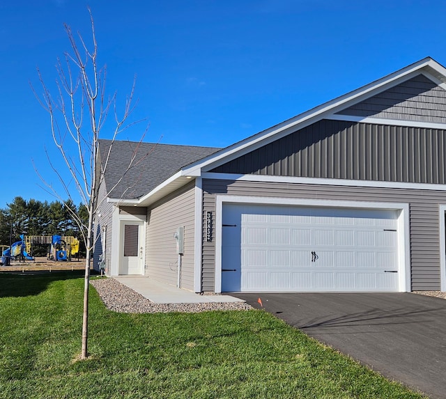 view of front of home featuring a front lawn, aphalt driveway, and a garage
