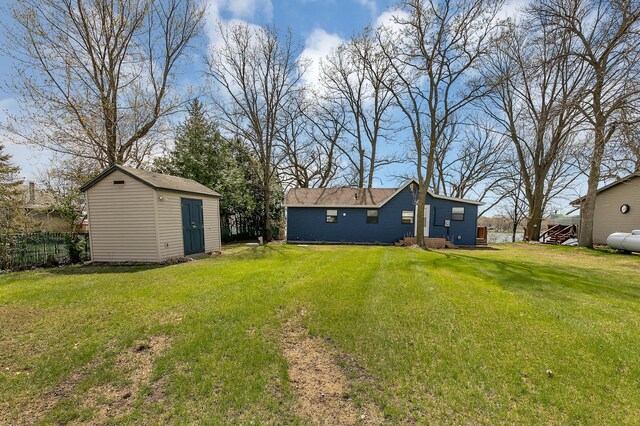 view of yard featuring fence, a storage unit, and an outdoor structure