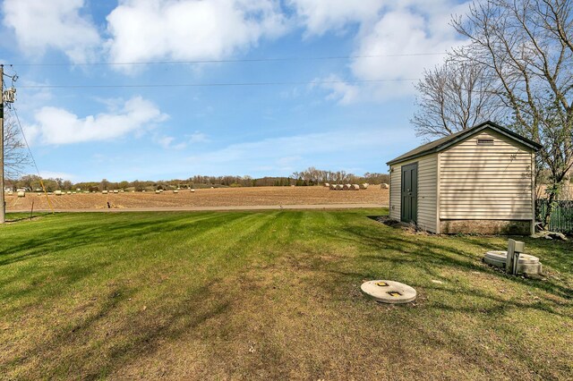 view of yard with an outbuilding, a storage shed, and a rural view