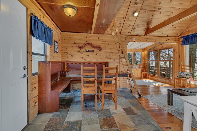 dining area with vaulted ceiling with beams, wooden walls, and wooden ceiling