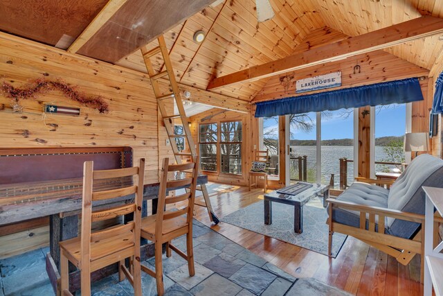 dining room featuring lofted ceiling with beams, a water view, wooden walls, and wooden ceiling