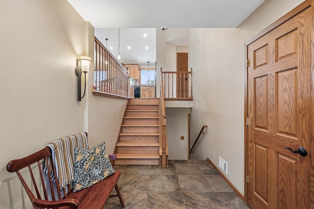 stairway with baseboards, visible vents, and stone finish floor